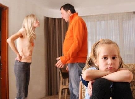 Divorced parents arguing in front of an upset child.