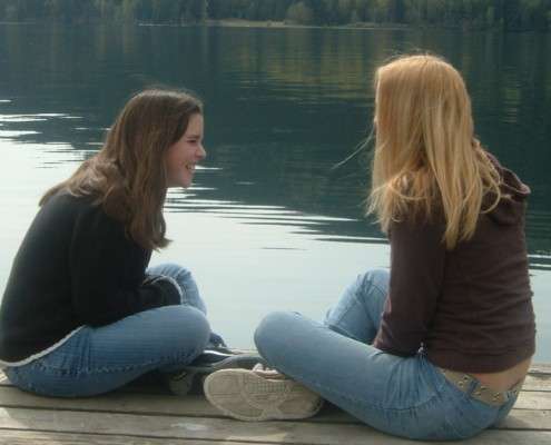 Two teen girls laughing on a pier. Peer counseling Austin tx