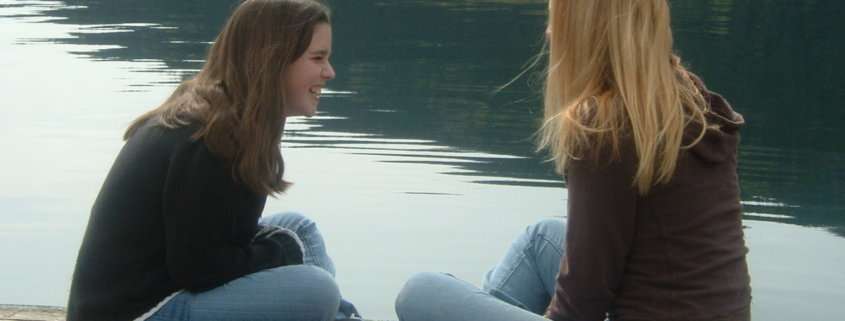Two teen girls laughing on a pier. Peer counseling Austin tx