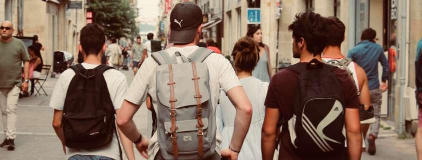 Preparing your kids for college. Four teens walking to college class with backpacks on.