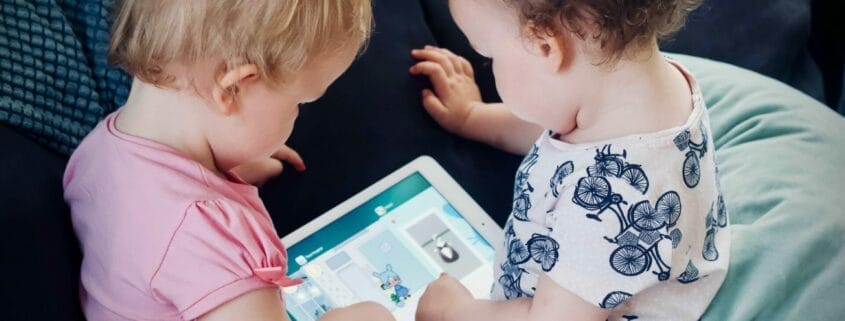 Two cute toddlers playing on an iPad tablet.