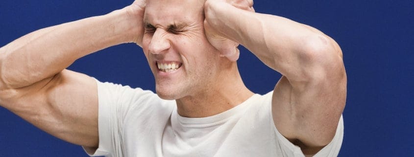 stressed man grimacing holding his head