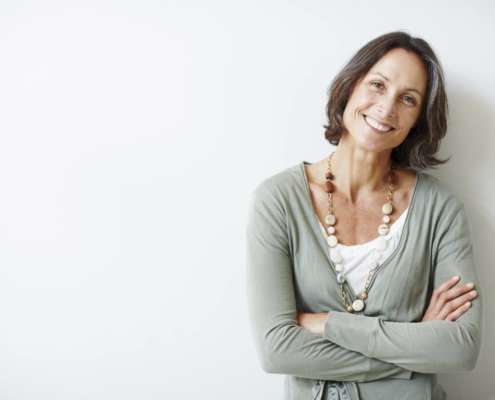 Self-aware woman smiling with folded arms.